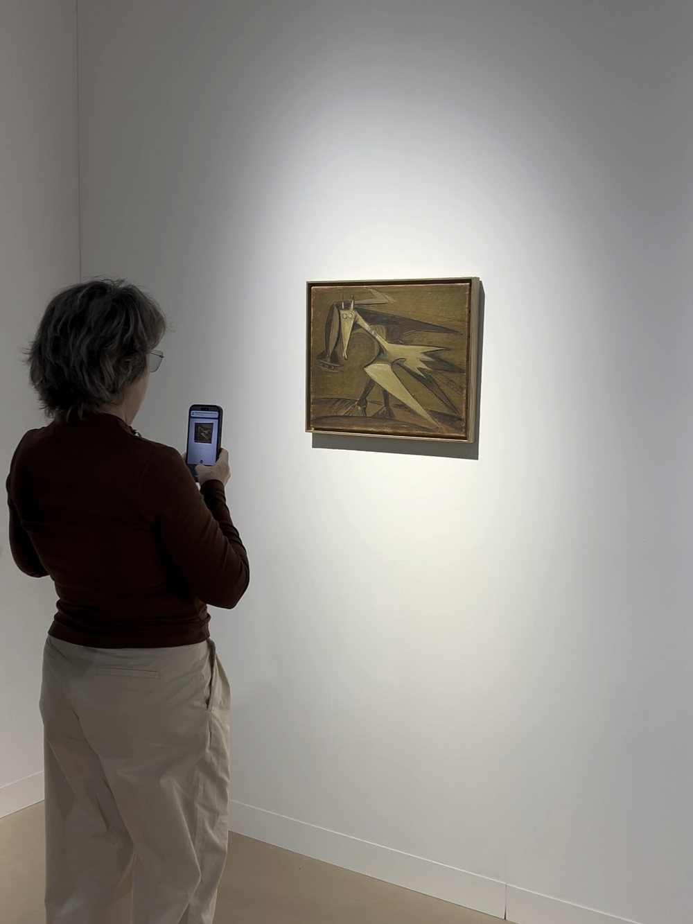 Visitante observando una pintura iluminada en una sala