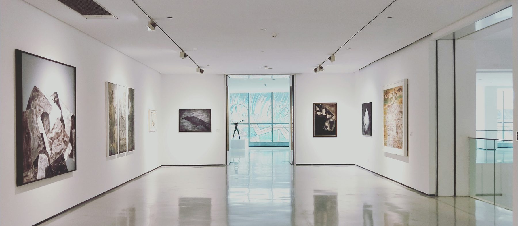 Interior de una sala de exposición con obra colgada y luz de riel